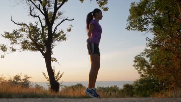 La fille saute de la corde dans le parc. Jeune fille faisant du sport dans la forêt près de la mer. La femme saute de la corde dans le parc. Une jeune fille fait du sport dans la forêt. Vidéo au ralenti — Video