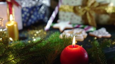 Hayat devam ediyor. Geleneksel Noel hediyelerine, ladin dallarına ve hediyelere karşı yanan kırmızı muma yakın çekim. İnanılmaz soyut bir arka plan. Şenlikli kış kutlaması. İyi tatiller..