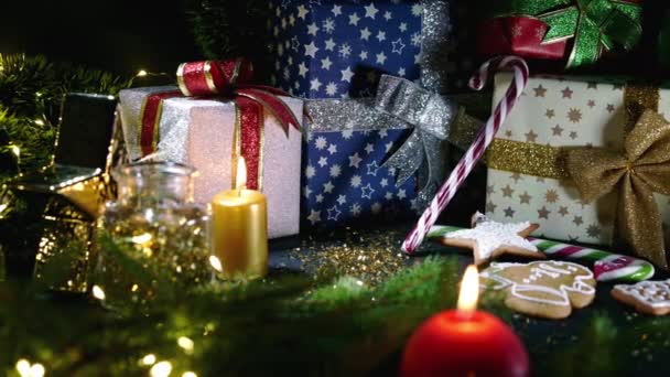 Natura morta - primo piano della candela rossa accesa contro i tradizionali regali di Natale, rami di abete rosso e regali. Incredibile sfondo astratto. Festeggiamenti invernali. Buone vacanze concetto. — Video Stock