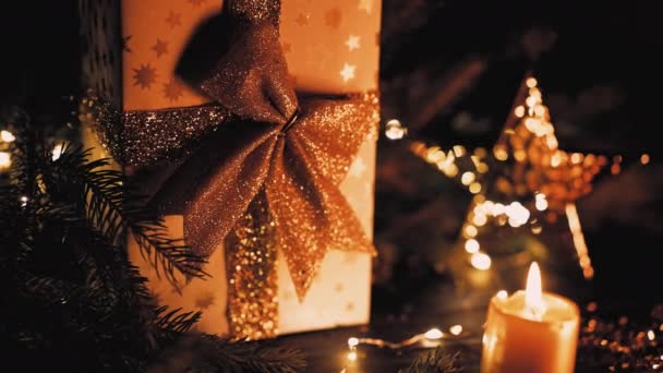 Χριστουγεννιάτικο φόντο - χρυσό κομψό κουτί δώρου με φιόγκο. Καίγοντας κερί και λαμπερό αστέρι ως σύμβολο των παραδόσεων. Χαρούμενες διακοπές. — Αρχείο Βίντεο