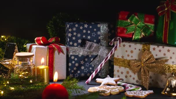 Los detalles tradicionales de la Navidad acogedora - la vela roja ardiente con los regalos, las ramas de abeto, las galletas de jengibre y las piruletas. Celebración festiva de invierno. Feliz concepto de vacaciones. — Vídeos de Stock