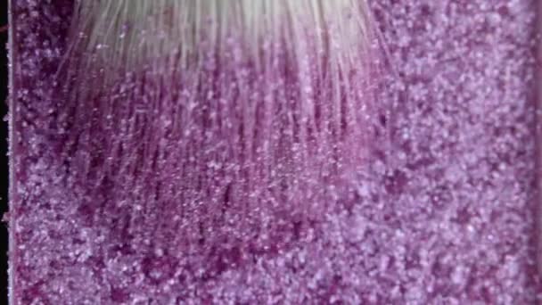 Impressionante close-up da paleta de sombra com partículas brilhantes. Processo de pegar pigmento na pilha do pincel pelo artista de maquiagem. Produtos publicitários, conceito de ferramentas cosméticas. — Vídeo de Stock