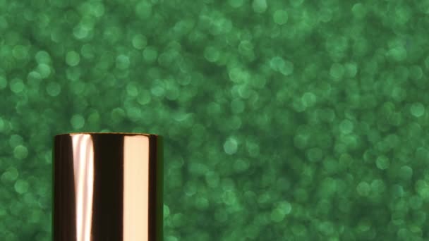 Lipstik keluar dari wadah dengan latar belakang hijau mengkilap. Showcase atau iklan untuk merek kecantikan, Konsep mode, kosmetik dengan ruang fotokopi — Stok Video