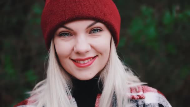 Portret młodej ładnej kobiety w lesie, sezon zimowy. Atrakcyjne rodzaju dziewczyna uśmiechnięta, pani w modnej koszuli i czerwony kapelusz czapka. — Wideo stockowe