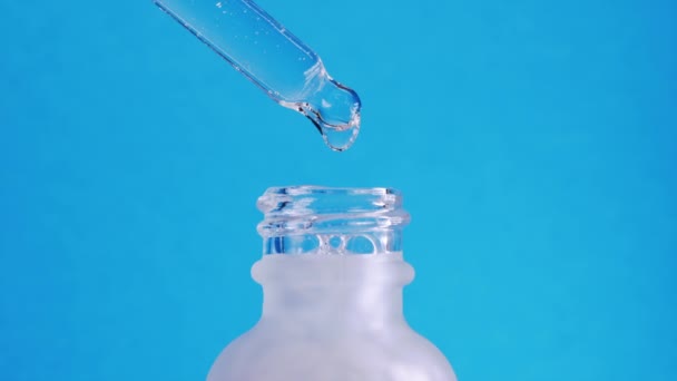 Hyaluronic acid essence dripping from pipette into frosted glass jar. Concept of hydration, healthy facial skin care, cosmetic products, smart consumption trend. Blue studio background. — Stock Video