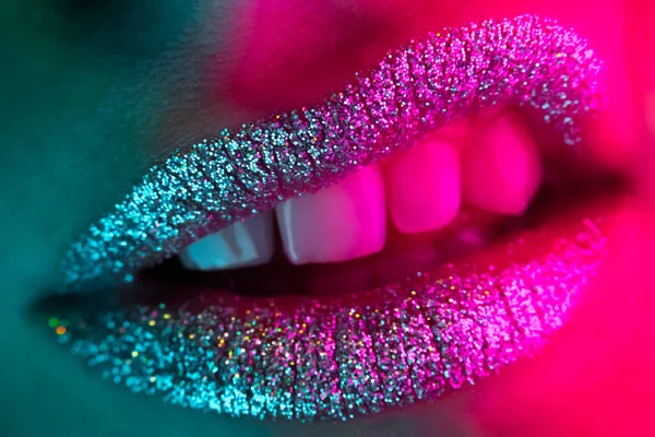 Close-up of displeased angry mouth gesture. Fashion woman grimacing with glowing metallic sparkles lipstick. Macro view of glamorous make-up.