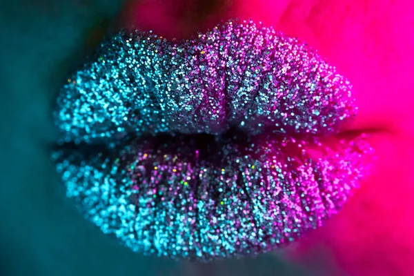 Sexy fashion model met glanzende sprankelingen op de lippen verzenden van lucht kus aan de camera. Macro uitzicht op vrouw met glamoureuze make-up. Uitgaansleven, nachtclub concept. — Stockfoto