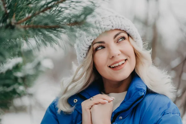 Ritratto di giovane bella donna nella foresta, stagione invernale. Attraente ragazza bionda gentile sorridente, signora in cappello bianco lavorato a maglia. — Foto Stock