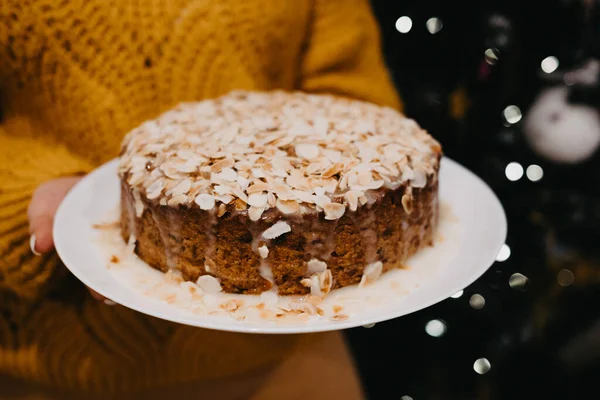 Mujer sosteniendo cupcake de Navidad con pétalos de almendra sobre fondo claro bokeh. —  Fotos de Stock