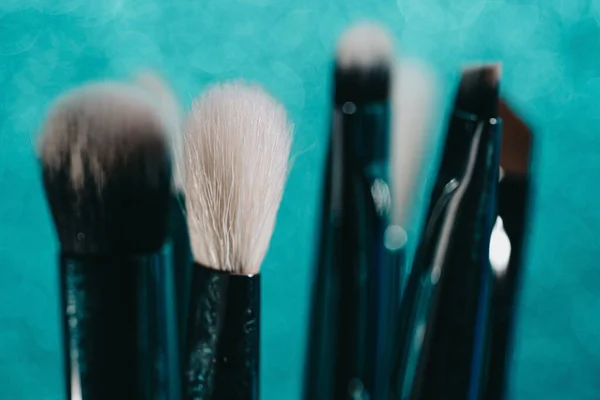 Cosmetics make-up brushes on blue sparkling background. — Stock Photo, Image