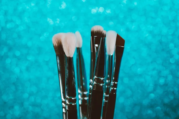 Cosmetics make-up brushes on blue sparkling background. — Stock Photo, Image