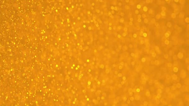 Glinsterende Gouden Deeltjes Met Bokeh. Geel goud onscherpe ronde facula. Natuurlijke drijvende organische abstracte deeltjes. Achtergrond. Kerstmis en Gelukkig Nieuwjaar. Langzame beweging. — Stockvideo