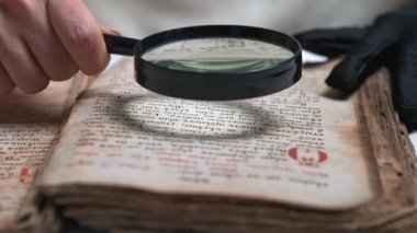 Eldivenli kadın araştırmacı büyüteçle antik kitapları araştırıyor. Edebiyatın bilimsel çevirisi. Eskiler 'in el yazmalarını araştırıyorum.