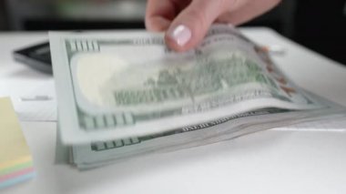 Kadın dolar sayıyor. Kadın muhasebeci ya da bankacı merkez büroda Amerikan para birimini sayar. Elinde yeni banknotlar var. İzleme finans, bütçe, tasarruf ve gider kavramı.