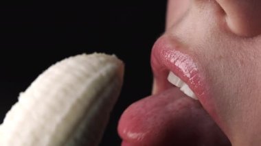 Seksi genç kadın baştan çıkarıcı bir şekilde taze muz yalıyor. Arzunun bayan yüz ifadesi makro görünümü. Kadın ağzına yakın çekim, şehvetli görüntüler. Yavaş çekim.