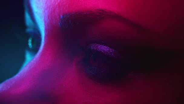 Occhio femminile, ritratto laterale. Donna con incredibile trucco brillante sera sotto luce al neon colorata. Bellezza, parte del corpo, concetto di cosmetici. — Video Stock