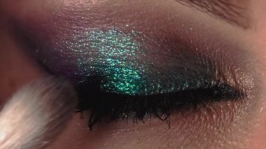 Makyaj sanatçısının, kadınların göz kapaklarına gölge uygulaması. Işıl ışıl parlayan güzel bir akşam makyajı. Ağır çekim. Güzellik, kozmetik konsepti