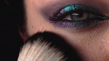 Makyaj sanatçısının, kadınların yanağına ve yüzüne pudra sürdüğü yakın çekim. Işıl ışıl parlayan güzel bir akşam makyajı. Ağır çekim. Güzellik, kozmetik konsepti