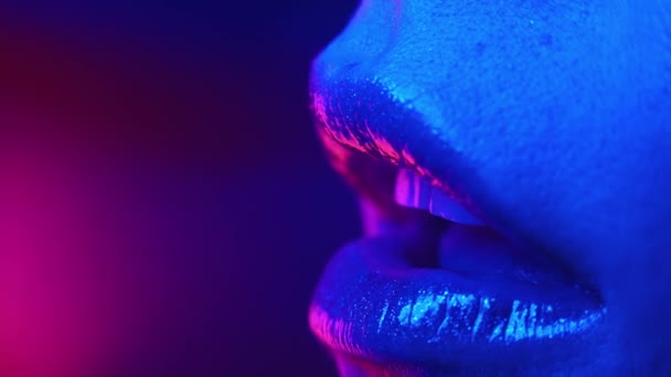 Сексуальная женщина соблазнительно облизывает губы языком. Красочный. неоновый свет. Макровзгляд на женское выражение лица желания. Ночная жизнь, концепция соблазна. Копирование пространства. — стоковое видео