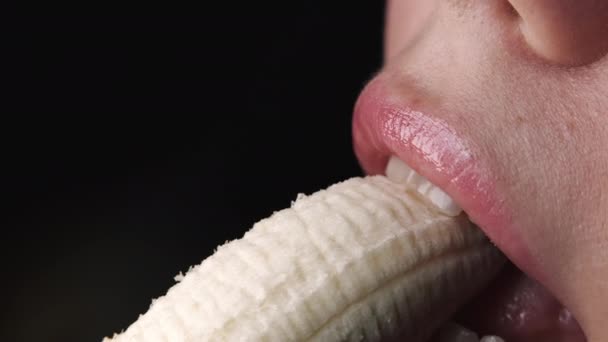 Sexy jeune femme mord séduisante et manger de la banane fraîche. Vue rapprochée de la bouche féminine, images sensuelles. Mouvement lent. — Video