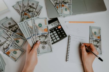 Kadın dolar sayıyor. Kadın muhasebeci ya da bankacı merkez büroda Amerikan para birimini sayar. Elinde yeni banknotlar var. İzleme finans, bütçe, tasarruf ve gider kavramı.