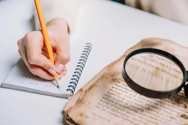 Investigador examina libro antiguo con lupa. Traducción científica de la literatura antigua. Estudiar manuscrito con escritos antiguos —  Fotos de Stock