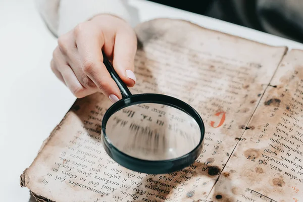 Tarihçi bilim adamı büyüteçle antik kitap okuyor. Dini edebiyatın çevirisi. İçinde antik yazılar olan el yazmaları. Geçmişin hazineleri. Müze parçası. — Stok fotoğraf
