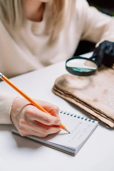 Mulher pesquisadora em luvas explora livro antigo com lupa. Tradução científica da literatura. Investigando manuscrito com escritos antigos — Fotografia de Stock