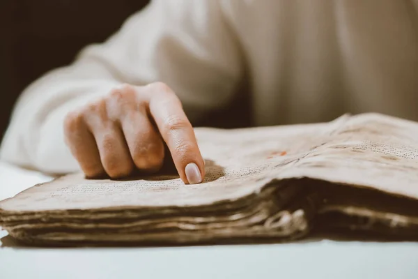 Mujer leyendo libro antiguo - Biblia. Concentrado atentamente sigue dedo sobre papel página en la biblioteca. Antiguos manuscritos de archivo. Concepto de historia. — Foto de Stock