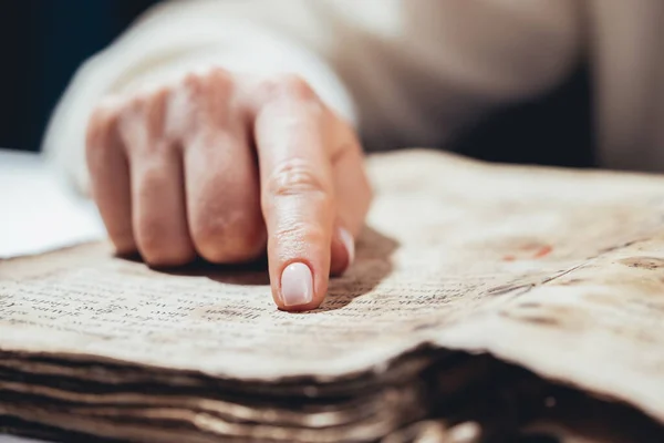 Mujer leyendo libro antiguo - Biblia. Concentrado atentamente sigue dedo sobre papel página en la biblioteca. Antiguos manuscritos de archivo. Concepto de historia. — Foto de Stock