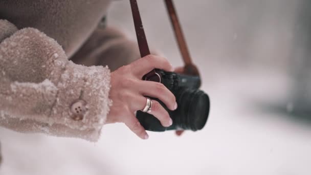 As mãos femininas estão segurando câmera digital estilo retro no fundo do inverno. A rapariga leva tiros. Uma verdadeira queda de neve. Movimento lento. — Vídeo de Stock