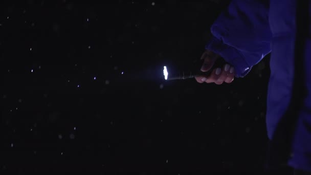 Main féminine tient une lampe de poche et brille la nuit, à la recherche de quelque chose. Hiver, chutes de neige, blizzard, temps froid. — Video