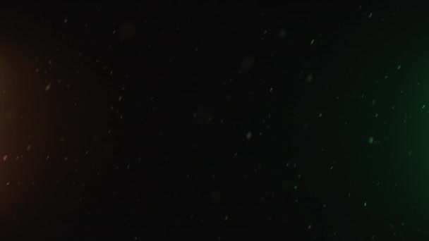 Natural snowfall, winter snow on black background with colorful orange and green light. Abstract white dust particles. Perfect for composite or transparency — Vídeo de Stock
