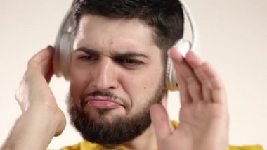 Beyaz arka planda kulaklıkla dans eden sakallı yakışıklı bir adam. Müzik, aktif dans, radyo konsepti, yavaş çekim