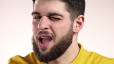 Sarı gözlü yakışıklı adam, kameraya flört ediyor ve gülümsüyor. Stüdyodaki adam beyaz arka planda.