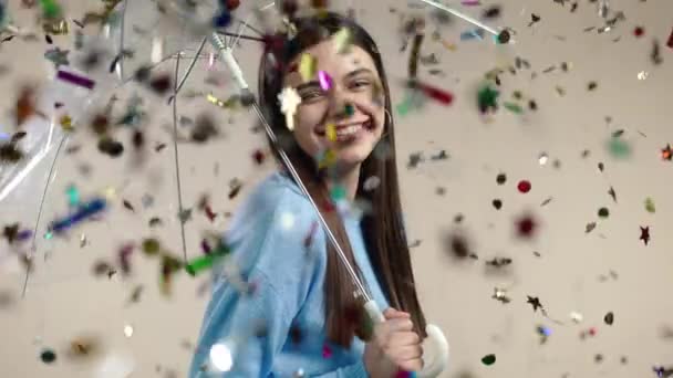 Mujer feliz está bajo el paraguas, se regocija por la lluvia de confeti en el estudio. Concepto de wow idea, celebración, fiesta, ganar — Vídeos de Stock