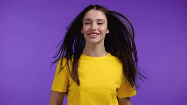 Wanita cantik menari di latar belakang studio ungu, rambut panjangnya berkibar dari aliran udara. Wanita dengan kaos kuning. Suasana hati yang positif. Gerakan lambat. — Stok Video
