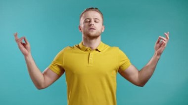 Sarılı sakin adam dinleniyor, meditasyon yapıyor. Sakinleşir, sarı stüdyo arka planında derin derin nefes alır. Yoga konsepti.