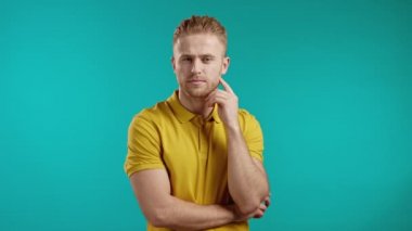 Düşünen adam mavi arka planda etrafa bakıyor. Düşünceli yüz ifadeleri. Yakışıklı sarışın model..