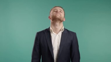 Yorgun genç iş adamının boynu ağrıyor. Takım elbiseli adam ara verir ve el masajıyla boyun kaslarını yoğurur..