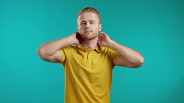 Vermoeide jongeman met pijn - nekpijn. Guy in casual geel t-shirt neemt pauze en kneedt pijnlijke nekspieren met handmassage. — Stockvideo