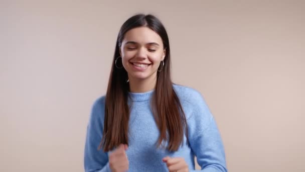 Donna che balla positiva sullo sfondo dello studio. Modello abbastanza femminile in maglione blu. Festa, felicità, libertà, concetto di gioventù. — Video Stock