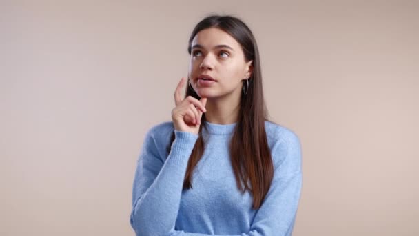 Femme pensante regardant vers le haut et autour sur fond de studio. Expressions pénibles du visage. Joli modèle avec une apparence attrayante — Video