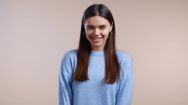 Ung kvinna med lång frisyr som tittar på kamera, flörtar. Vacker modell flicka på ljus studio bakgrund. — Stockvideo