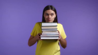 Menekşe arka planda gülümseyen kadın kütüphaneden bir yığın üniversite kitabı tutuyor. Kız gülümsüyor, mezun olduğu için mutlu..