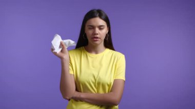Kadın mendilin içine hapşırıyor. Violet stüdyosundaki izole kız. Bayan hasta, soğuk ya da alerjik reaksiyon gösteriyor. Coronavirus, salgın hastalık konsepti 2021.