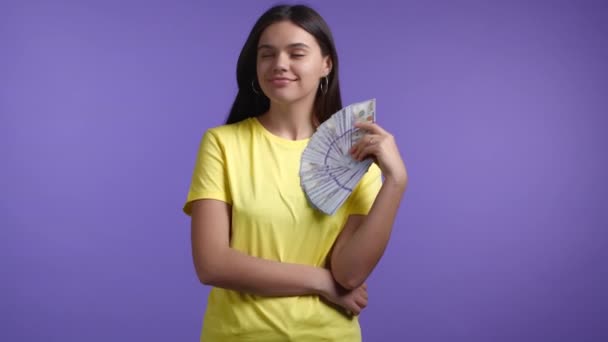 Glimlachende gelukkige vrouw met contant geld - USD valuta dollars bankbiljetten op violette muur. Symbool van jackpot, winst, overwinning, het winnen van de loterij — Stockvideo