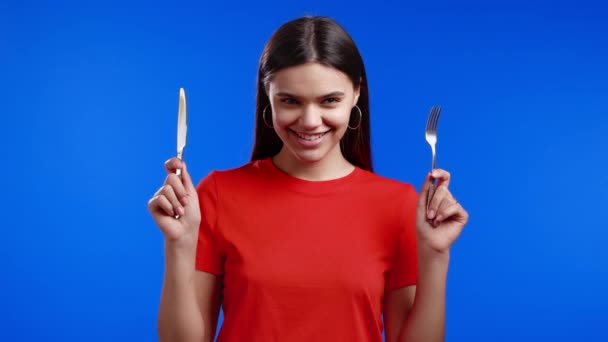 포크와 칼을 든 귀여운 굶주린 여자의 모습. 푸른 스튜디오 배경에 커리 와 함께 식탁에 오르기를 기다리고 있는 소녀. — 비디오