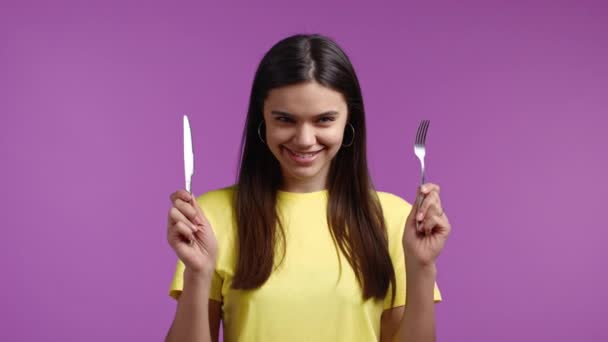 포크와 칼을 든 굶주린 여자의 모습. 분홍색 녹음실 배경에 커리와 함께 저녁 식사를 준비하고 있는 소녀. — 비디오