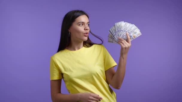 행복 한 여인에게 현금 - 미국 달러 지폐를 보라색 벽에 붙인 것이다. 착암기의 상징, 이득, 승리, 복권 당첨 — 비디오